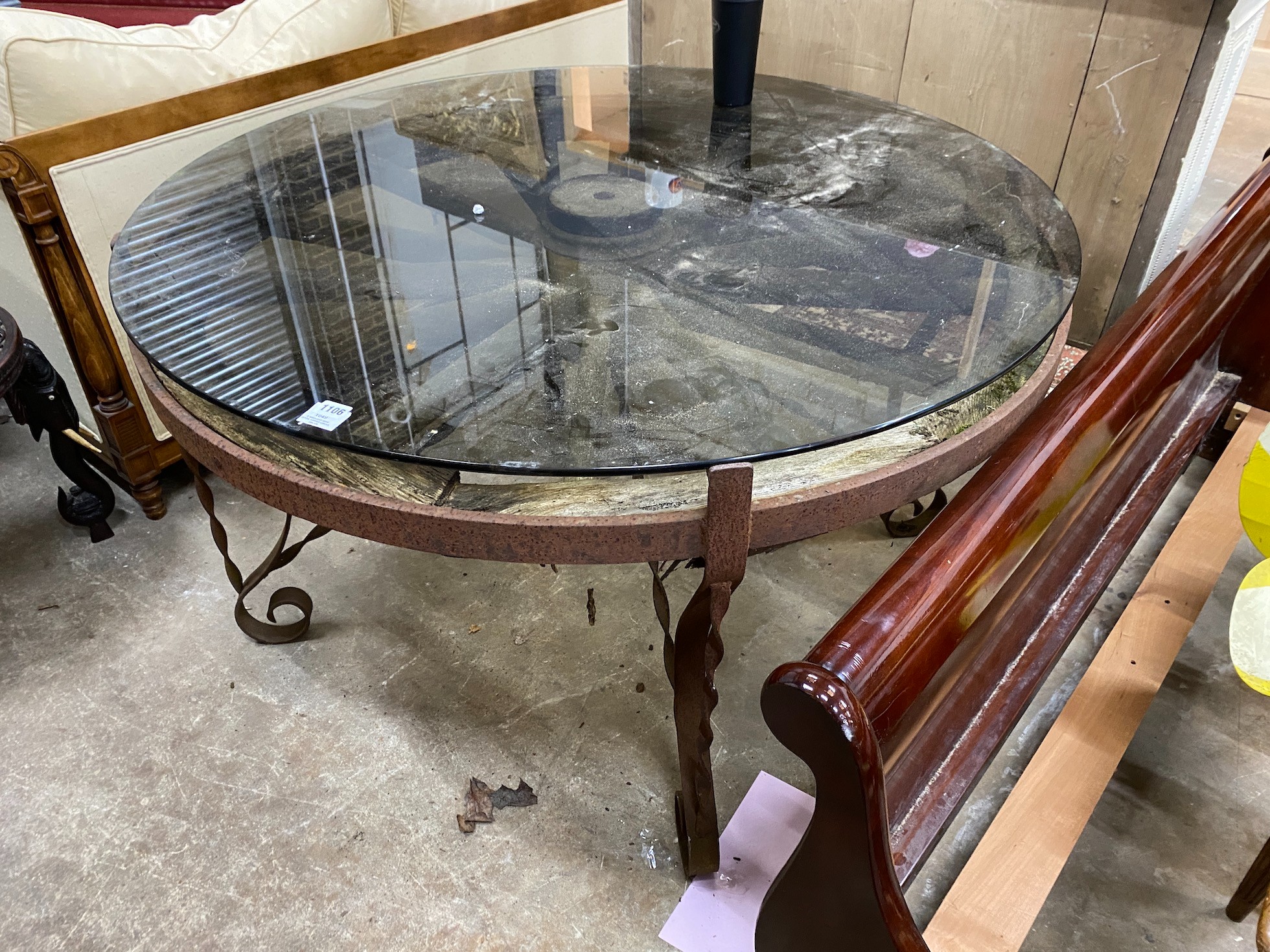 A wrought iron glass topped circular cartwheel garden table, diameter 124cm, height 72cm